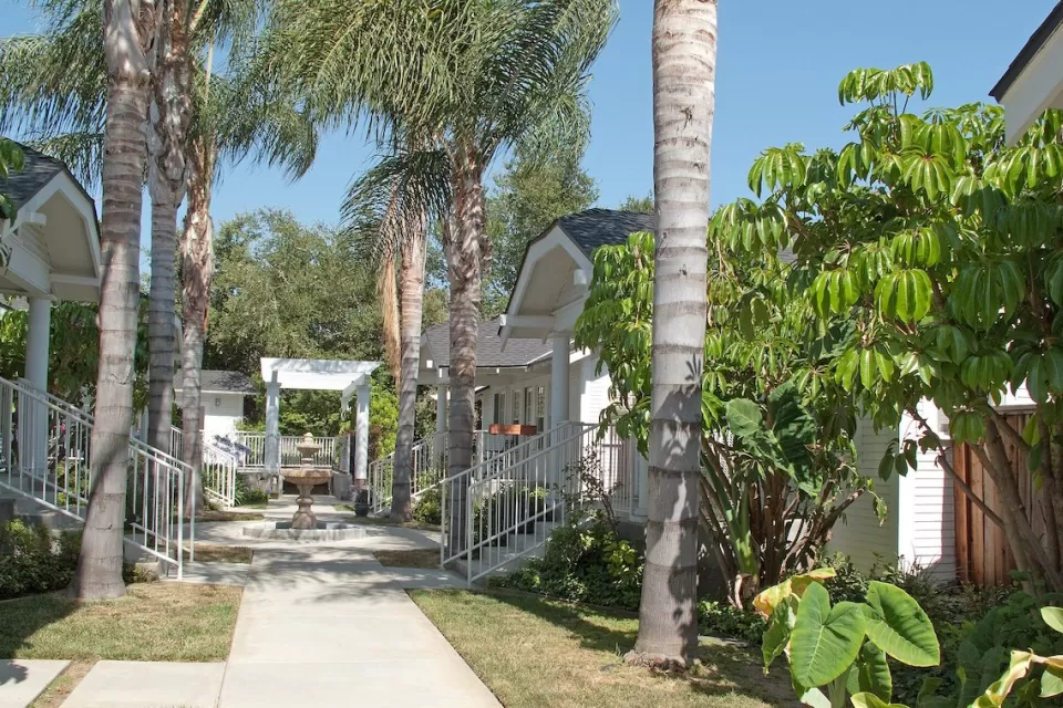One-story bungalow court complex in Pasadena, California with leafy green palm trees.
